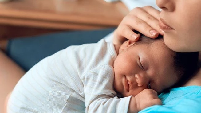 Mom holding baby as he sleeps on her chest