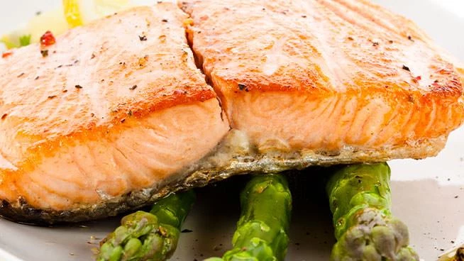 Close up of salmon sitting atop grilled asparagus
