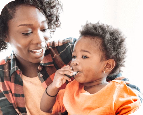 Mamá sosteniendo al niño que está comiendo