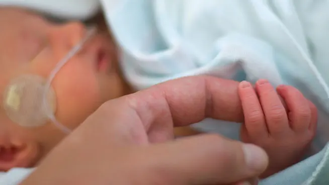 Bebé prematuro sosteniendo el dedo de su padre