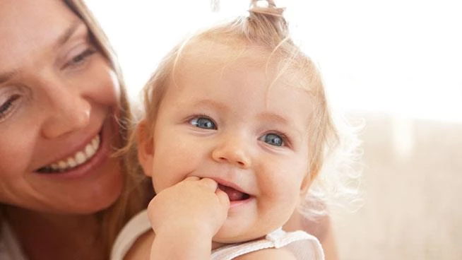 Mom holding smiling daughter