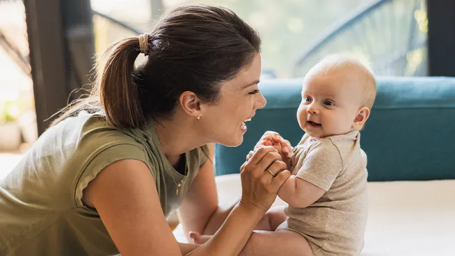 Mom holding baby's hands while baby learns to sit up